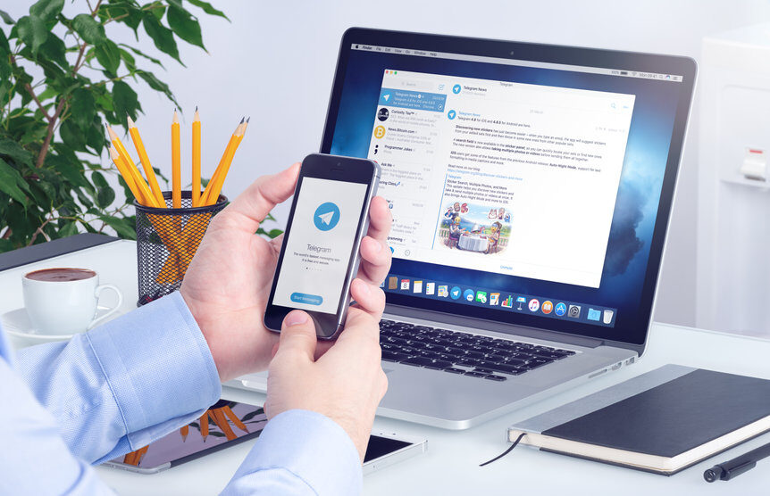 varna-bulgaria-january-23-2018-telegram-messenger-on-iphone-screen-in-male-hands-and-desktop-version-of-telegram-on-macbook